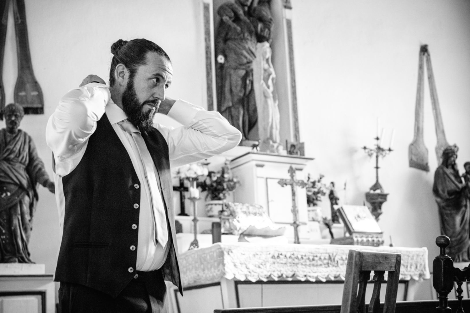 dans la Chapelle du Domaine du Chalonge, le marié en costume met sa cravate pour finir de se préparer pour son mariage